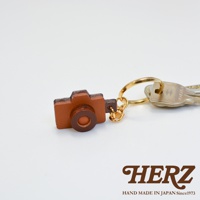 職人手作皮革相機造型鑰匙圈，咖啡色皮革製作，搭配金色鑰匙圈，風格簡約。