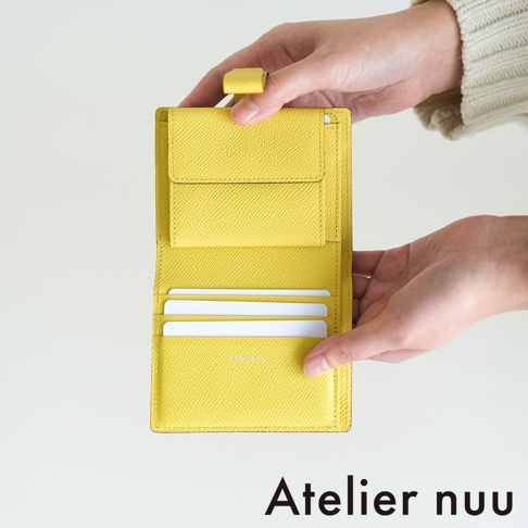Atelier nuu 品牌黃色皮革雙折短夾，展示了內部卡槽和零錢袋。