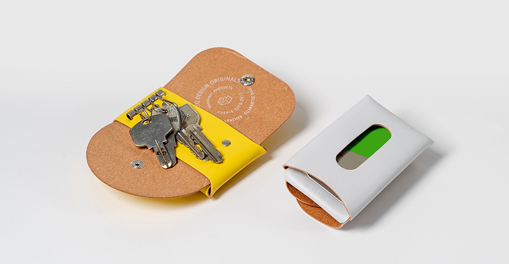 皮革製的黃色鑰匙包和白色卡片夾，皆置於白色背景上。