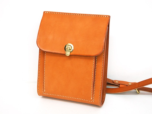 咖啡色厚實皮革單肩包，綴有金色鎖扣和精細縫線，配有可調節皮革肩帶。