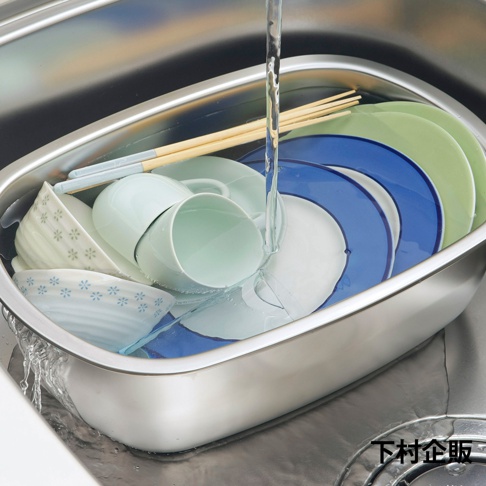 不鏽鋼洗菜洗碗盆內裝有綠色、藍色及白色盤子，淺綠色杯子，以及有花紋的白色碗。盆中還有木質筷子，水流正從上方注入。