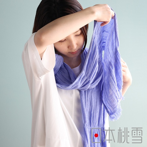 一位女性模特兒正專注地將淡紫色紗布圍巾圍繞在頸部，圍巾呈現細緻的抓皺質感，材質輕盈透氣，照片右下角印有日本桃雪品牌標誌與文字。