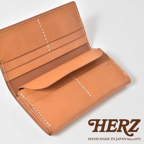 打開的HERZ品牌職人手作皮革長夾，採用淺棕色植鞣革製成，內側具備多層卡片夾層與翻蓋設計，呈現溫潤的皮革質感與精細的手縫車線細節，右下角壓印有HERZ品牌標誌。