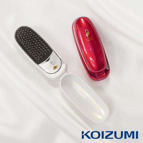 白色負離子音波磁氣美髮梳，梳頭為黑色，配有充電座，整體呈橢圓形，蓋子為鏡面紅色，上面印有金色標誌。