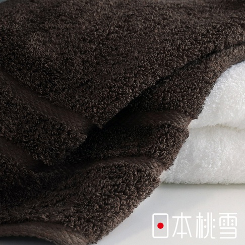 深棕色與白色毛巾堆疊，展現蓬鬆柔軟的棉質觸感。
