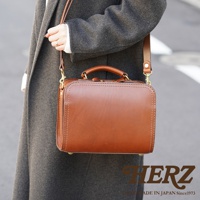 職人手作皮革兩用方形單肩包，展示為經典棕色，採用光滑皮革材質，搭配頂部提把及可拆卸肩帶，金屬扣件增添質感。