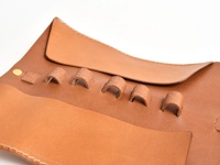 職人手作皮革捲捲收納筆袋，淺棕色天然皮革製成，袋面有五個皮革環，可固定筆類，另有金屬扣件。