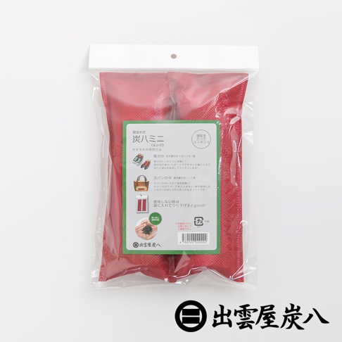 一組兩入的紅色鞋靴專用調濕木炭，包裝上印有日文說明及產品細節，材質為透氣布料，內部可見黑色顆粒狀木炭。