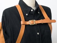 職人手作皮革背包用胸前扣帶，寬 3cm，採用天然棕色皮革製成，附有黃銅色金屬扣環和铆釘，可調節長度，連接於背包肩帶之間。