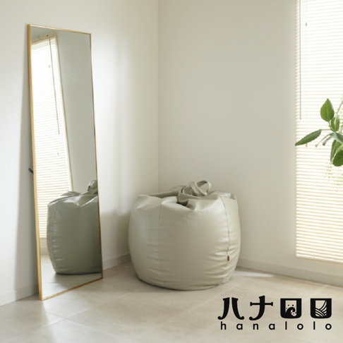 淺灰色皮革懶骨頭沙發，玉子造型，頂部有提把，置於室內角落，旁邊有一面金色鏡子。