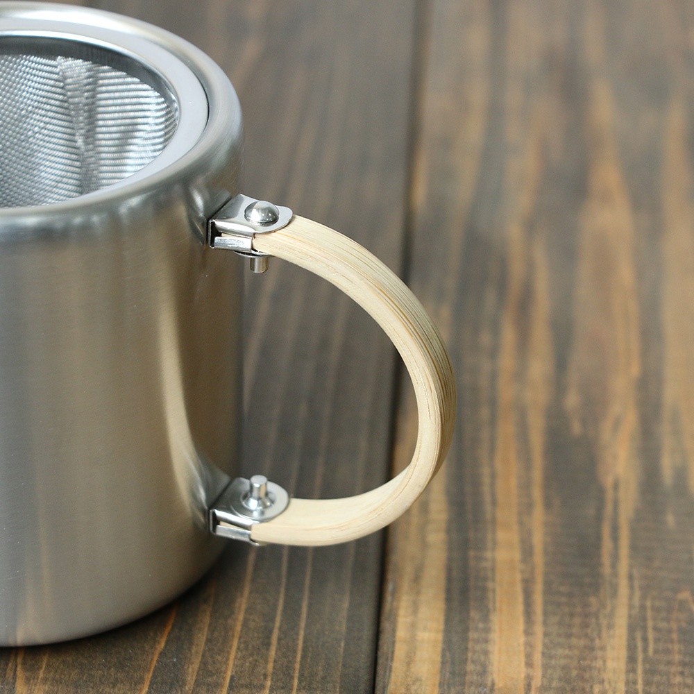 霧面不鏽鋼直筒茶壺，配備木質側邊提把，壺嘴旁有細緻的濾網。