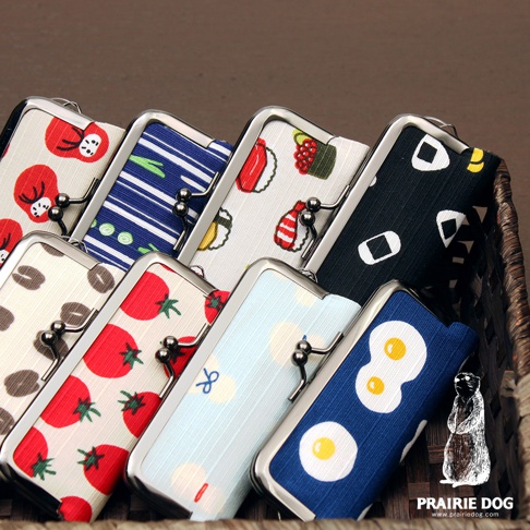 和布華印鑑收納口金包，展示多款印花設計，包括壽司、飯糰、番茄、咖啡豆、煎蛋與藍色條紋等圖案。包體採用布質材質，搭配金屬口金開闔。