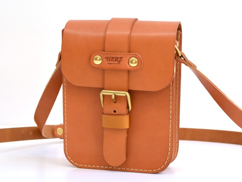 職人手作皮革經典皮扣單肩包，採用天然棕色皮革，帶有金色皮扣和鉚釘，設計簡潔，適合日常攜帶。