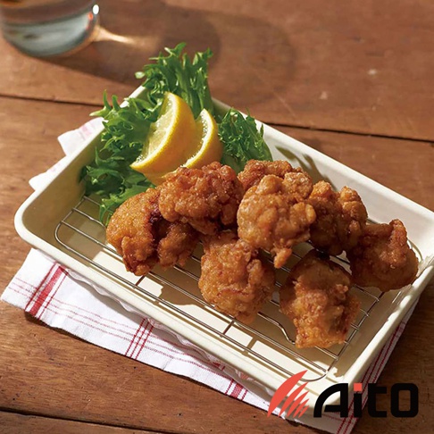 美濃燒釉彩萬用長方烤盤，白色烤盤內盛放著數塊炸雞、綠色生菜及兩片檸檬，置於金屬網架上，下方鋪有紅白色格紋餐巾，背景為木質桌面。