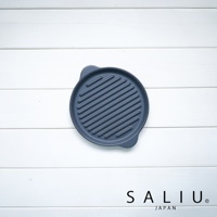 深灰色圓形陶製烤盤，表面有均勻的條狀紋路，兩側有小提把，置於白色木紋背景上。