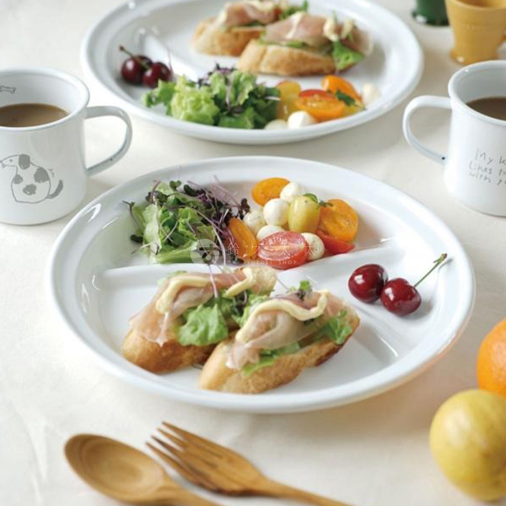 CAT&DOG 琺瑯分隔餐盤，白色圓形，有三個分隔區，盤內盛有沙拉、小番茄、莫札瑞拉起司球及火腿吐司，盤旁另有馬克杯及水果。
