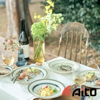 Anyware 美濃燒葉紋復古溫潤主食深盤，盤面帶有葉紋圖案，邊緣飾有藍色與金色的線條。盤內盛有食物，置於鋪有白色桌布的木桌上，旁邊有玻璃杯、酒瓶和鮮花。