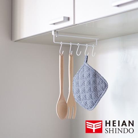 白色金屬製無痕櫥櫃掛架，掛有兩個木質餐具和一個藍白條紋隔熱墊。