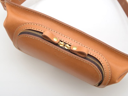 職人手作皮革拉鍊旅行斜背包，採用棕褐色皮革，搭配黃銅色拉鍊與金屬鈕扣，縫線精緻，設計簡約實用。
