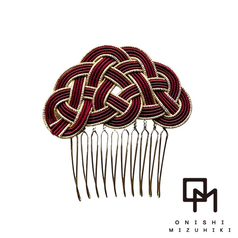 這是一款和風水引金絲髮叉，以深紅色絲線編織成複雜的結繩圖案，搭配金色的細絲勾勒邊緣，共有多種顏色可選。金色的髮叉梳齒整齊排列，設計精緻。