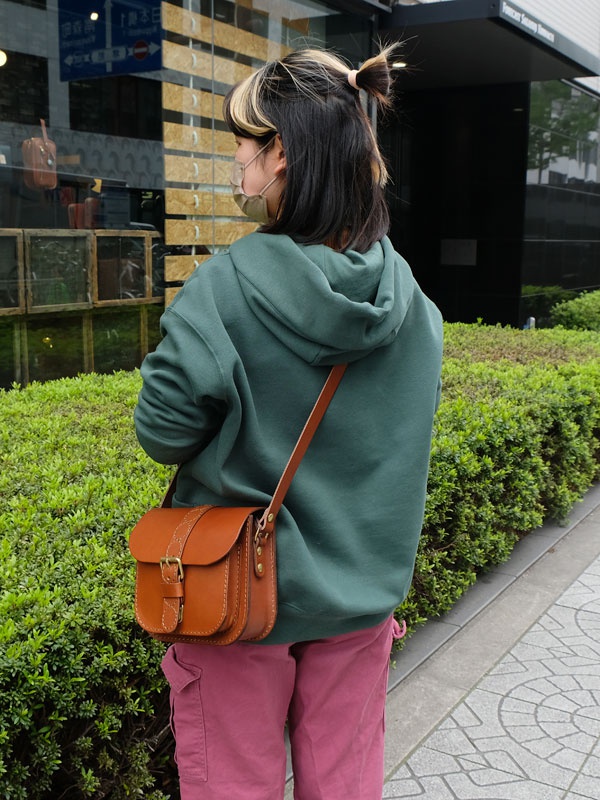 咖啡色皮革單肩包，方形包體，翻蓋設計，配有金屬扣環和可調式皮質背帶，包身有十字繡紋理。