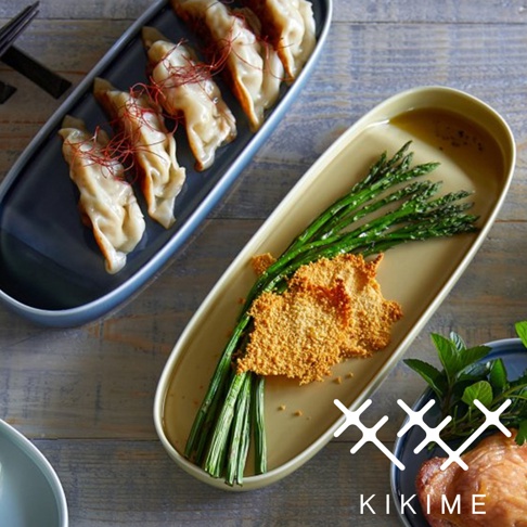 兩個波佐見燒長型主菜盤，一個裝有煎餃，上面撒有辣椒絲；另一個盤子裝有蘆筍和炸雞塊。