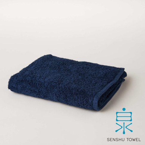 深藍色SOLID浴巾，材質蓬鬆柔軟，觸感細緻，表面有緞澤長纖紋理，右下角有品牌標誌。