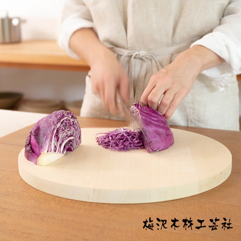 淺色木質圓形砧板，表面有切碎的紫甘藍。