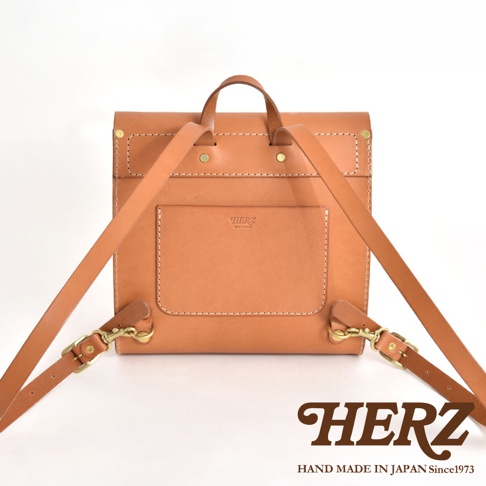職人手作皮革翻蓋迷你後背包，呈現自然原色鞣製皮革，帶有經典翻蓋設計與前方貼袋，搭配可調整式皮革背帶與金屬扣環。
