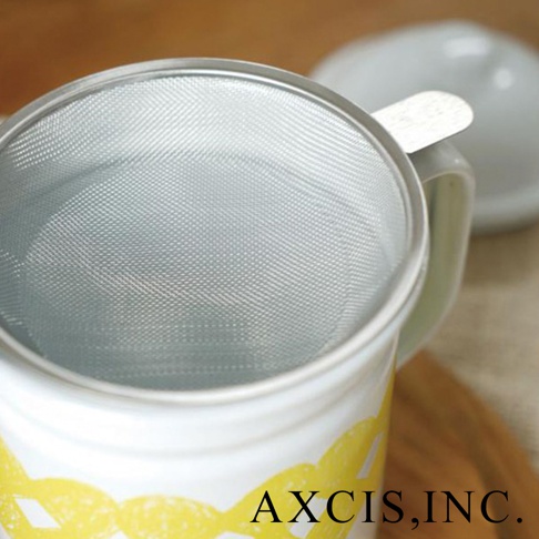 白色琺瑯濾油壺，壺身帶有黃色網狀圖案，壺口裝有細緻的金屬濾網，旁邊有一個淺色壺蓋。