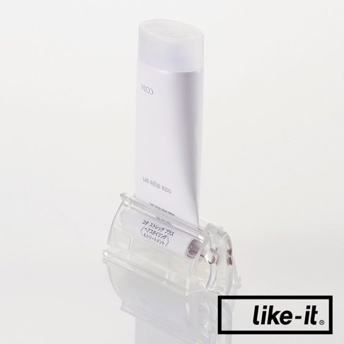 透明壓克力材質的手動轉轉擠牙膏夾，夾著一管白色牙膏，牙膏上有日文標示。