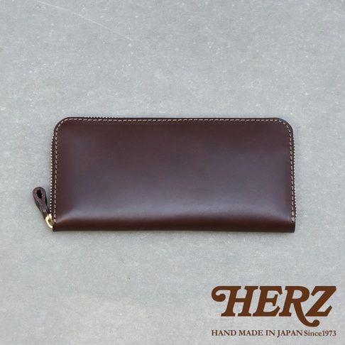 深棕色皮革製的拉鍊長夾，採用職人手作工藝，設有拉鍊開合與皮革拉環，材質呈現光滑細緻的質感。