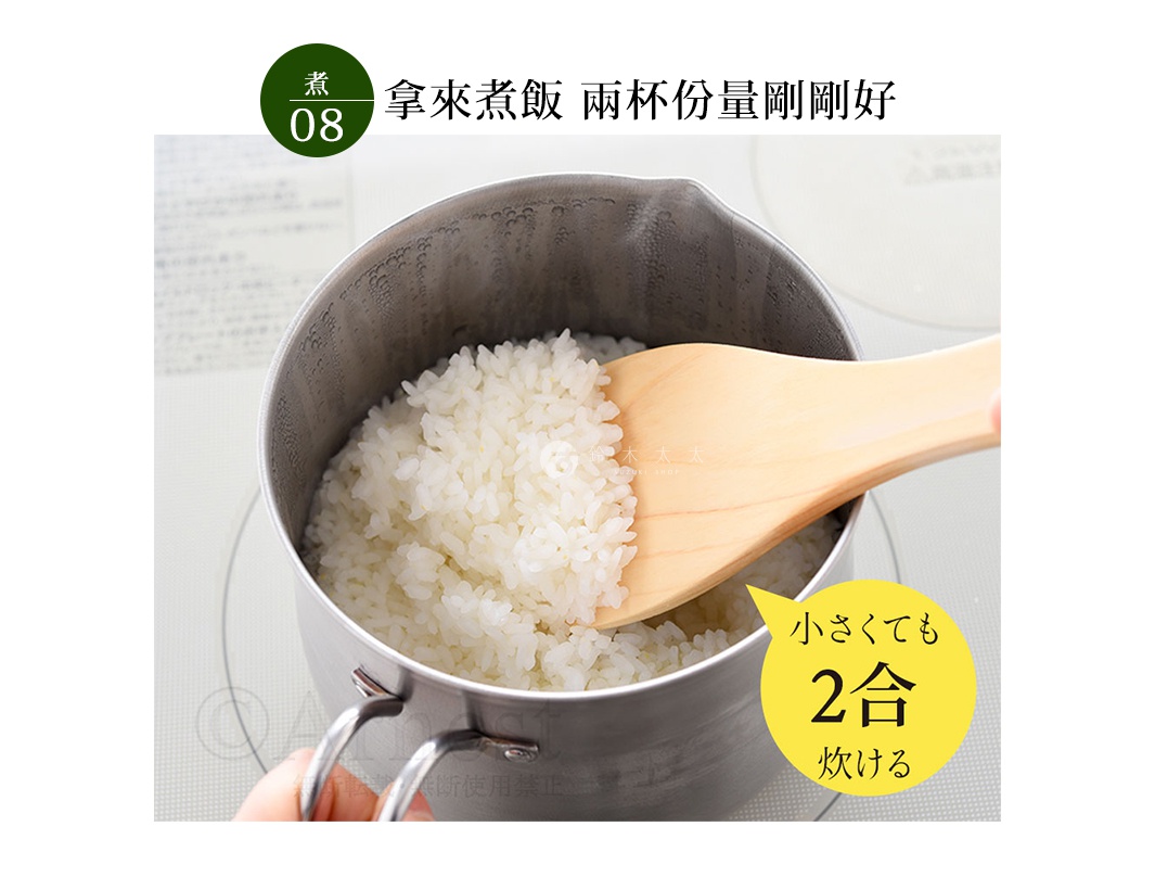 不鏽鋼料理鍋內盛滿白飯，木製飯勺正從鍋中舀起米飯。鍋身為銀色不鏽鋼材質，有兩個金屬提把。