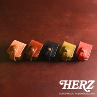 五個職人手作皮革原子釦型腰間小物收納包，顏色由左至右分別為淺棕、深棕、黑色、橄欖綠、紅色。每個收納包皆為皮革材質，有著原子釦設計，可繫於腰間。