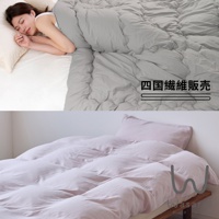 一位女子在床上睡覺，蓋著灰色被子，下方是粉色被套和枕頭。