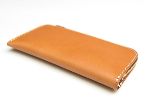 職人手作皮革L型拉鍊長夾，採用光滑的棕褐色皮革製成，設有金色拉鍊和手工縫線細節。