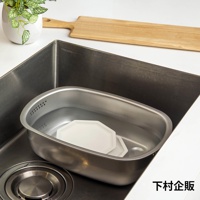 不鏽鋼水槽內放置一個帶有濾孔的不鏽鋼洗菜洗碗盆，盆中裝有水，並有兩個白色八角形盤子。