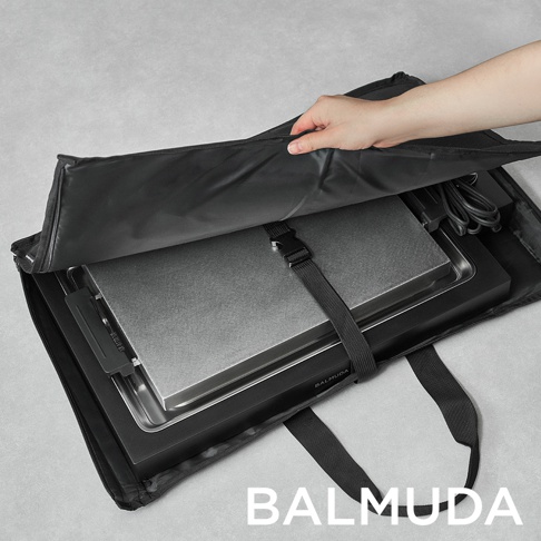 極致電烤盤 (黑色) 放置於黑色收納袋中，烤盤表面為金屬材質，配有束帶固定。