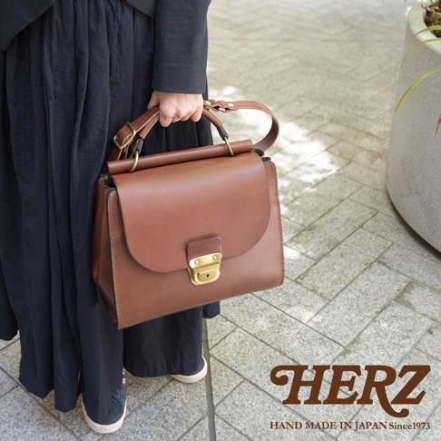 日本HERZ 職人手作皮革屋瓦風兩用單肩包，簡約設計搭配復古金屬鎖扣，手提或肩背皆有型，採用堅韌的Latigo牛皮革製作。
