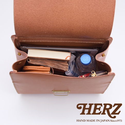 日本HERZ職人手作皮革屋瓦風兩用單肩包，內部裝有書本、水瓶、筆記本和錢包。