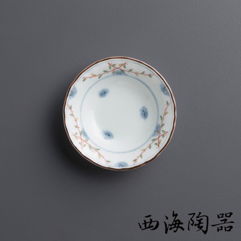 白色陶瓷小碟，邊緣飾有棕色釉，碟身內側繪有淡藍色小花和綠色藤蔓圖案，呈現日式風格。