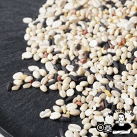 一堆混合的穀物，包含多種米類和豆類，顏色有白色、淺褐色、黑色和少量紅色，質地顆粒分明。