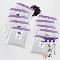 一堆古來炭迷你調濕木炭包，每包皆為淺灰色網狀材質，頂部有紫色紙質邊緣，中心印有黑色圖案和中文標籤。旁邊散落著黑色炭粒。