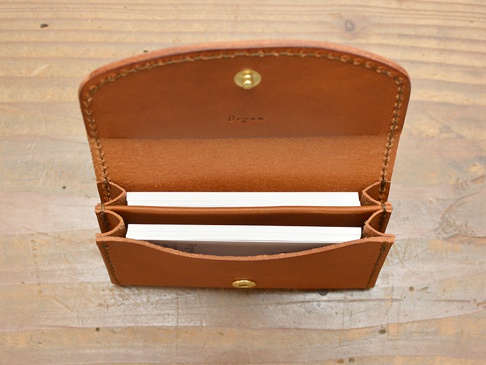職人手作皮革Organ商務用名片夾，淺棕色皮革，設有兩個夾層，可收納名片，上方蓋子以金色按扣固定，內部皮革上印有「Organ」字樣。