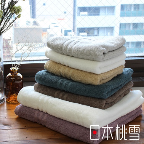 堆疊的今治飯店毛巾，顏色包含淺灰、白色、米色、深藍綠、咖啡色、奶白色及淡紫色，質地柔軟，毛巾邊緣有織紋裝飾。