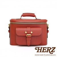 HERZ 品牌復古紅色皮革相機包，帶有翻蓋口袋和金色扣環，頂部有提把。