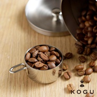 日製18-8不鏽鋼儲豆罐，附有10克量匙，罐身為銀色不鏽鋼材質，盛裝著淺棕色的咖啡豆。