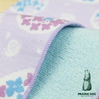 一塊淡紫色印有可愛卡通蝸牛和花朵圖案的方巾，邊緣縫有淺紫色滾邊，下方露出淺藍色的毛巾布料，右下角有一隻戴著太陽眼鏡的土撥鼠插畫及PRAIRIE DOG字樣。