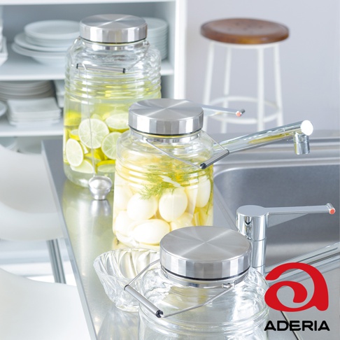 兩個玻璃梅酒罐，一個裝有檸檬片，另一個裝有醃漬物，均配有不鏽鋼蓋和撈杓，擺放在廚房檯面上。