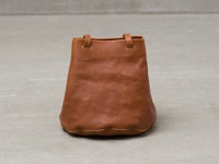 棕色皮革製成的抽繩肩背手提托特包，包身呈現圓潤的桶狀，底部有波浪狀的縫線設計，配有兩個短提把。